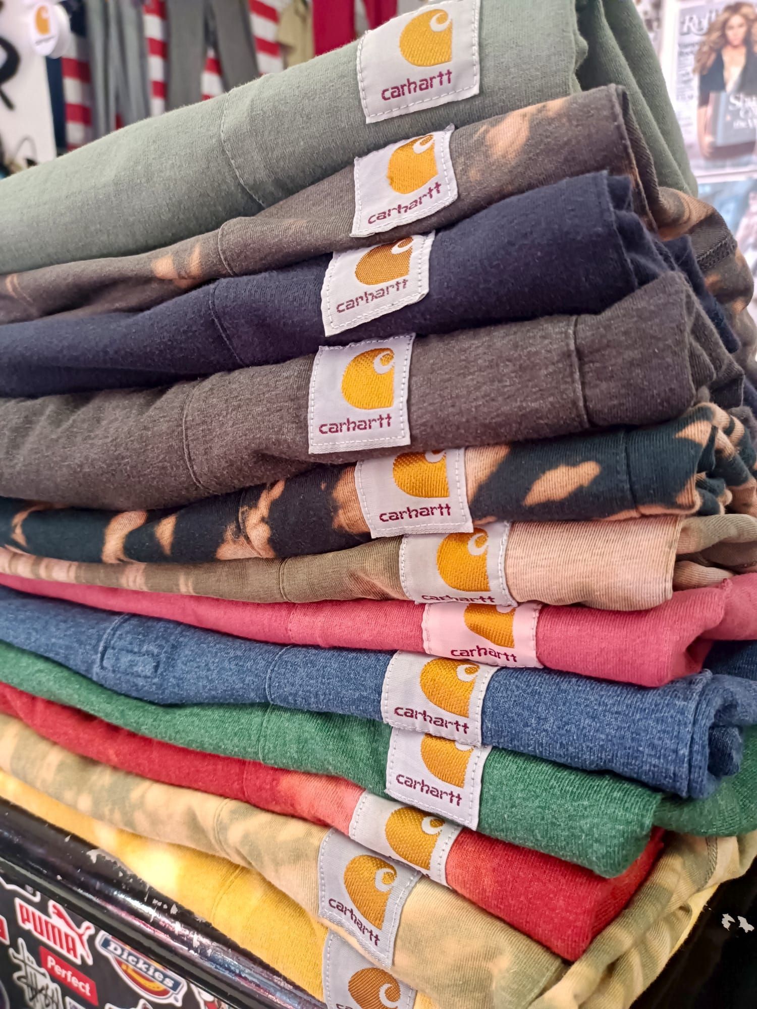 Pila di magliette piegate di vari colori con etichette di marca attaccate
