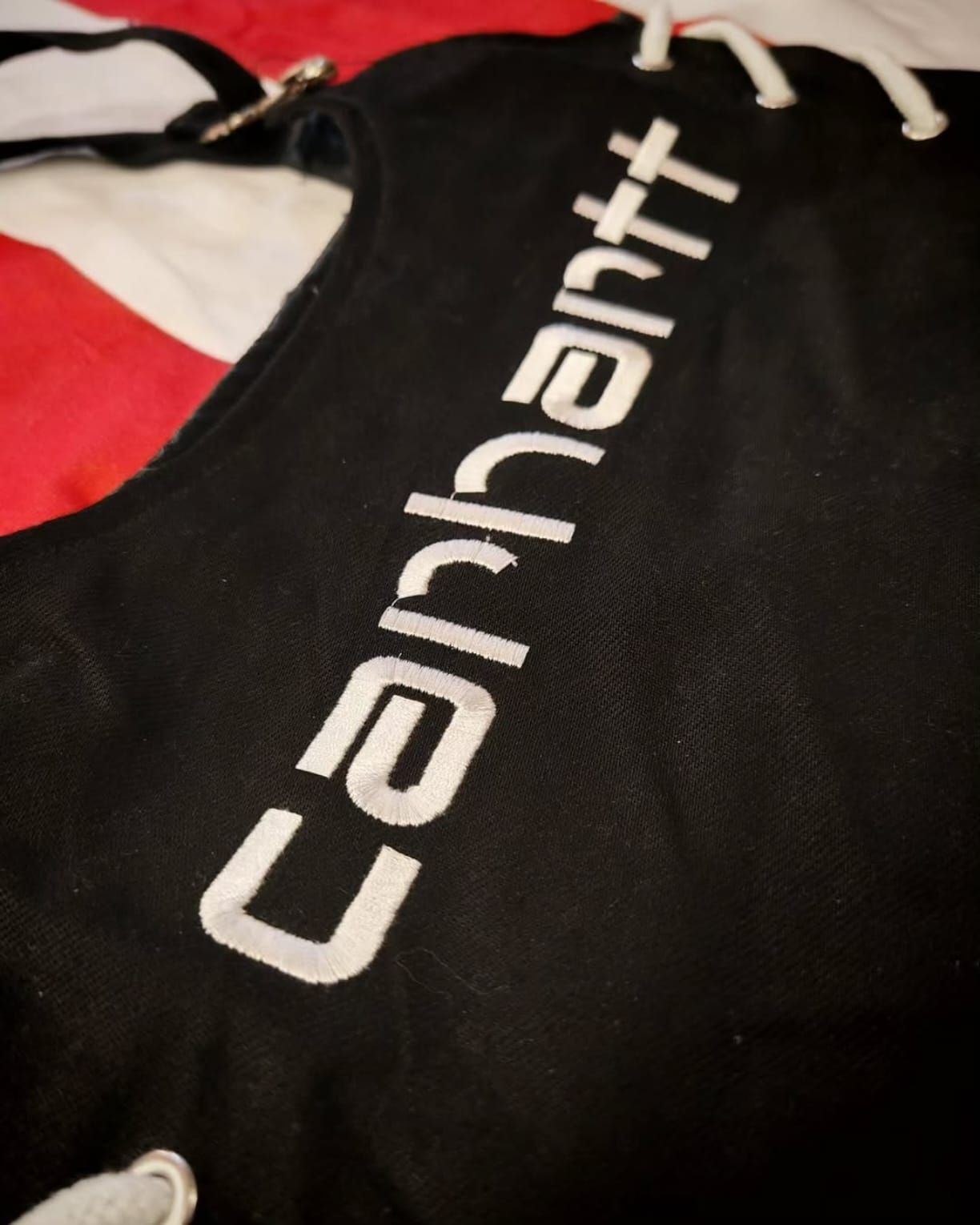 Borsa Carhartt nera con logo bianco su sfondo rosso e bianco