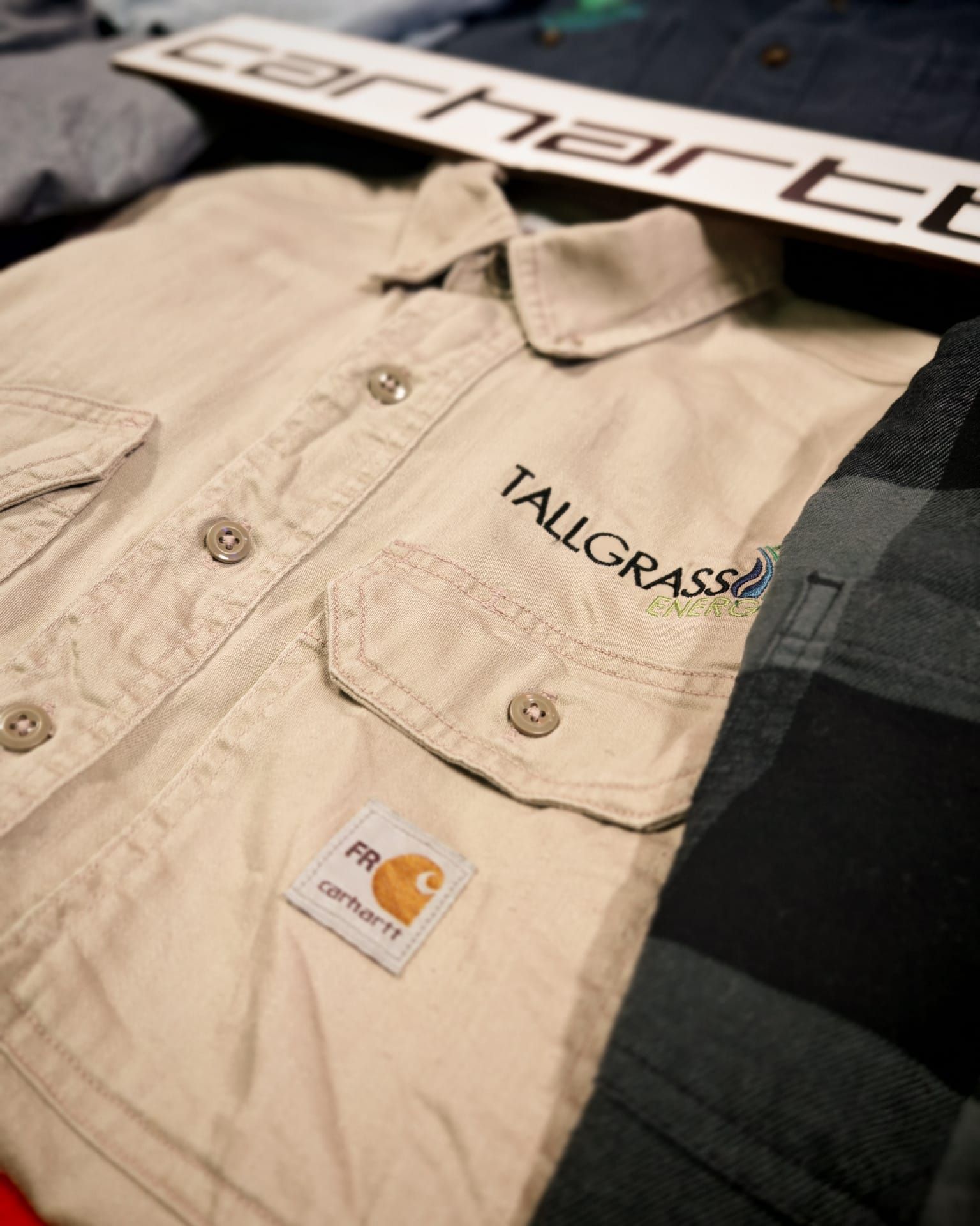 Camicia beige Tailgate TAILGATE con bottoni, tasche sul petto e cartellino pendente, su tessuto scuro.