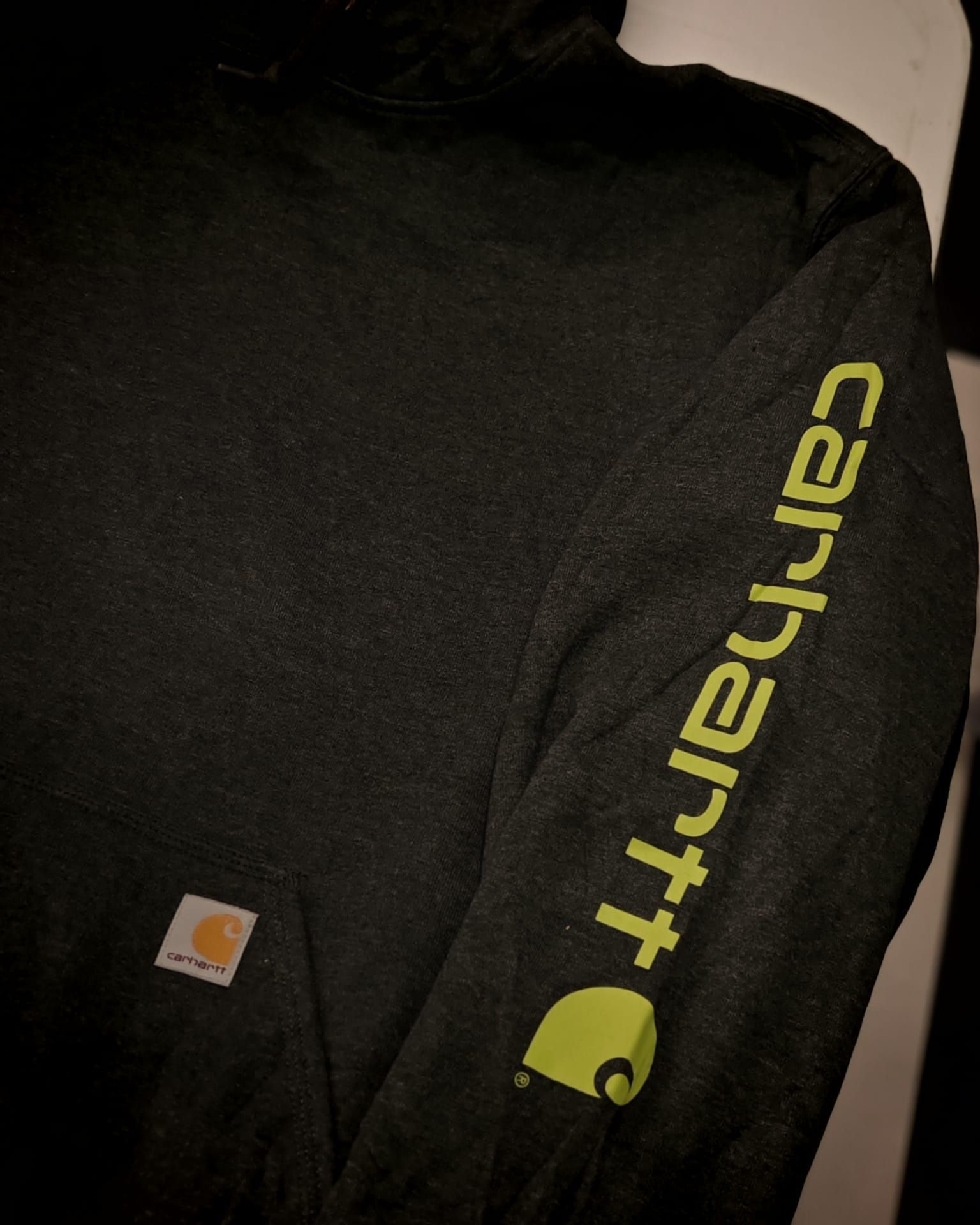 Felpa nera Carhartt con logo giallo fluo sulla manica.