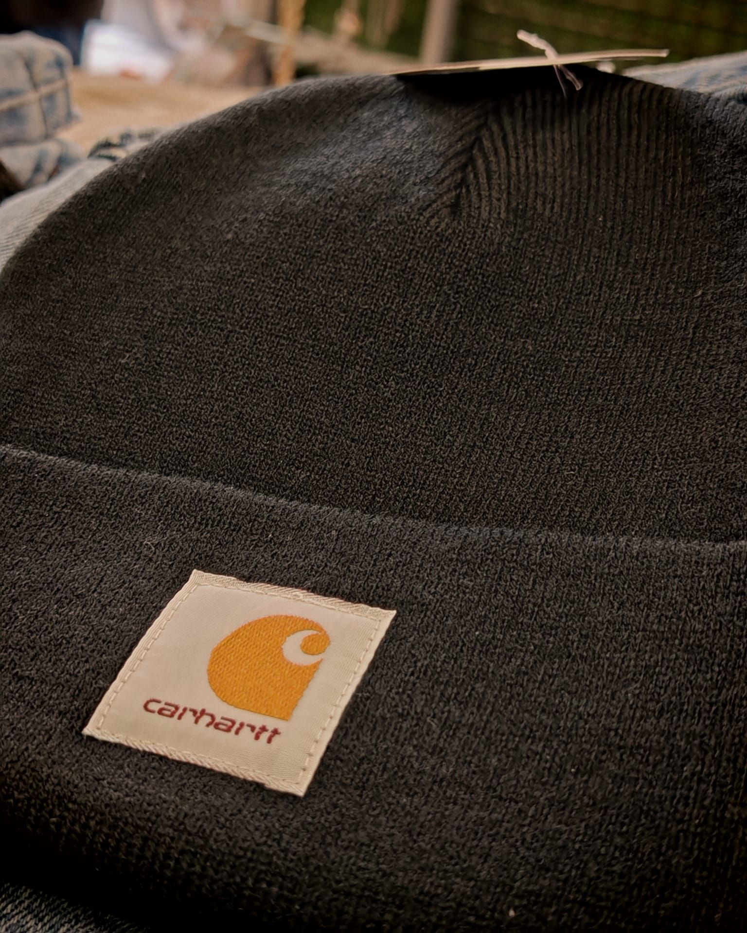 Primo piano di un berretto di lana nero della Carhartt con una toppa con logo color cuoio.