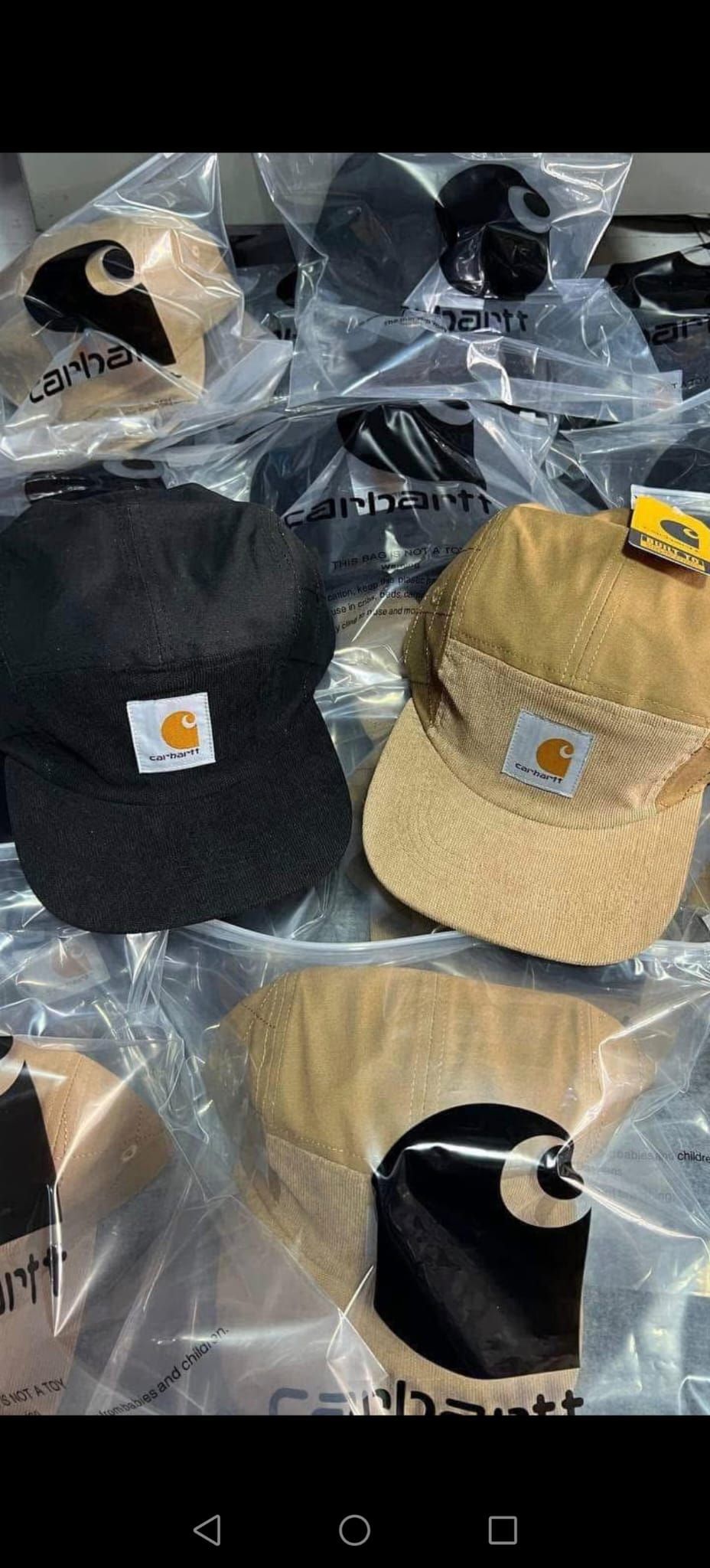 Assortimento di cappellini da baseball in confezione di plastica, tra cui modelli neri, marrone chiaro e beige con logo ricamato.