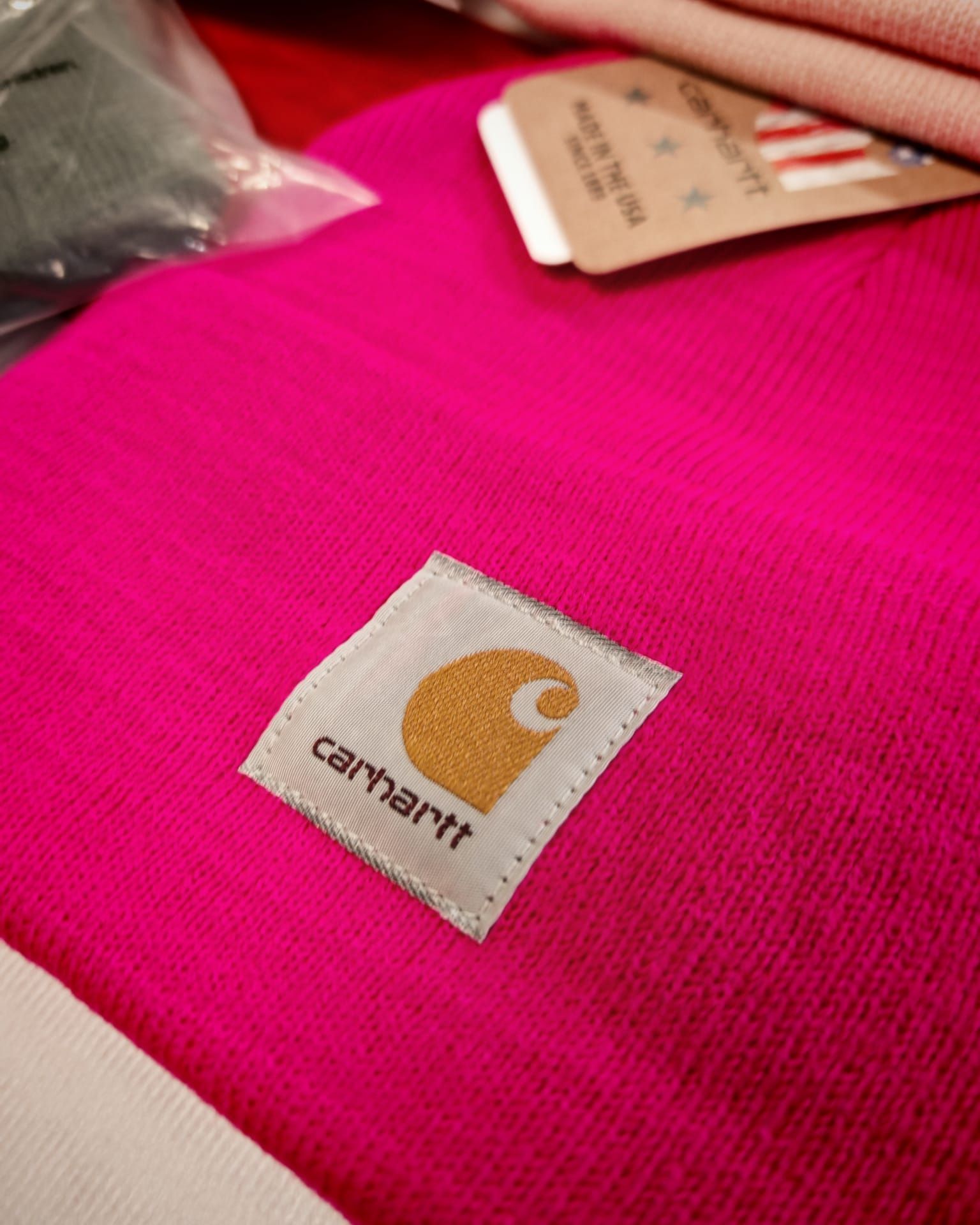 Toppa con logo Carhartt su un capo in tessuto rosa acceso (primo piano)