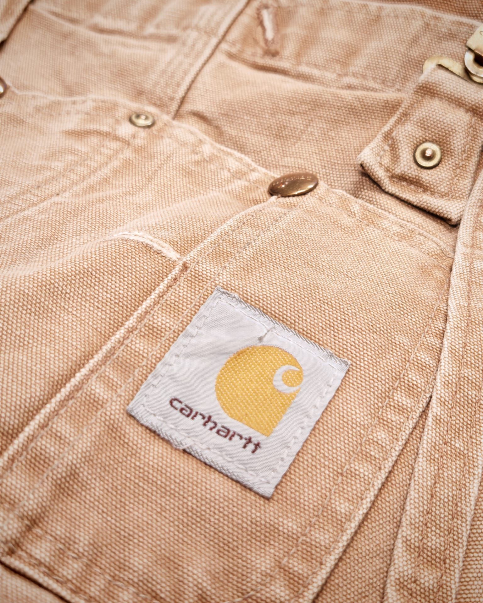 Primo piano di pantaloni Carhartt color kaki con la toppa del logo ben visibile.