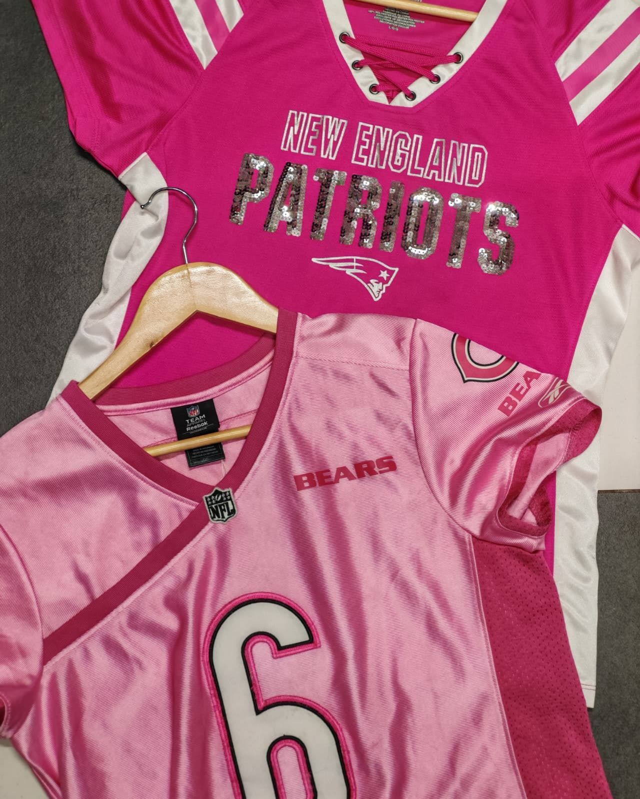 Due maglie rosa dei New England Patriots erano appoggiate su una superficie grigia, una con il numero 6 e l'altra con strisce bianche sulle maniche.