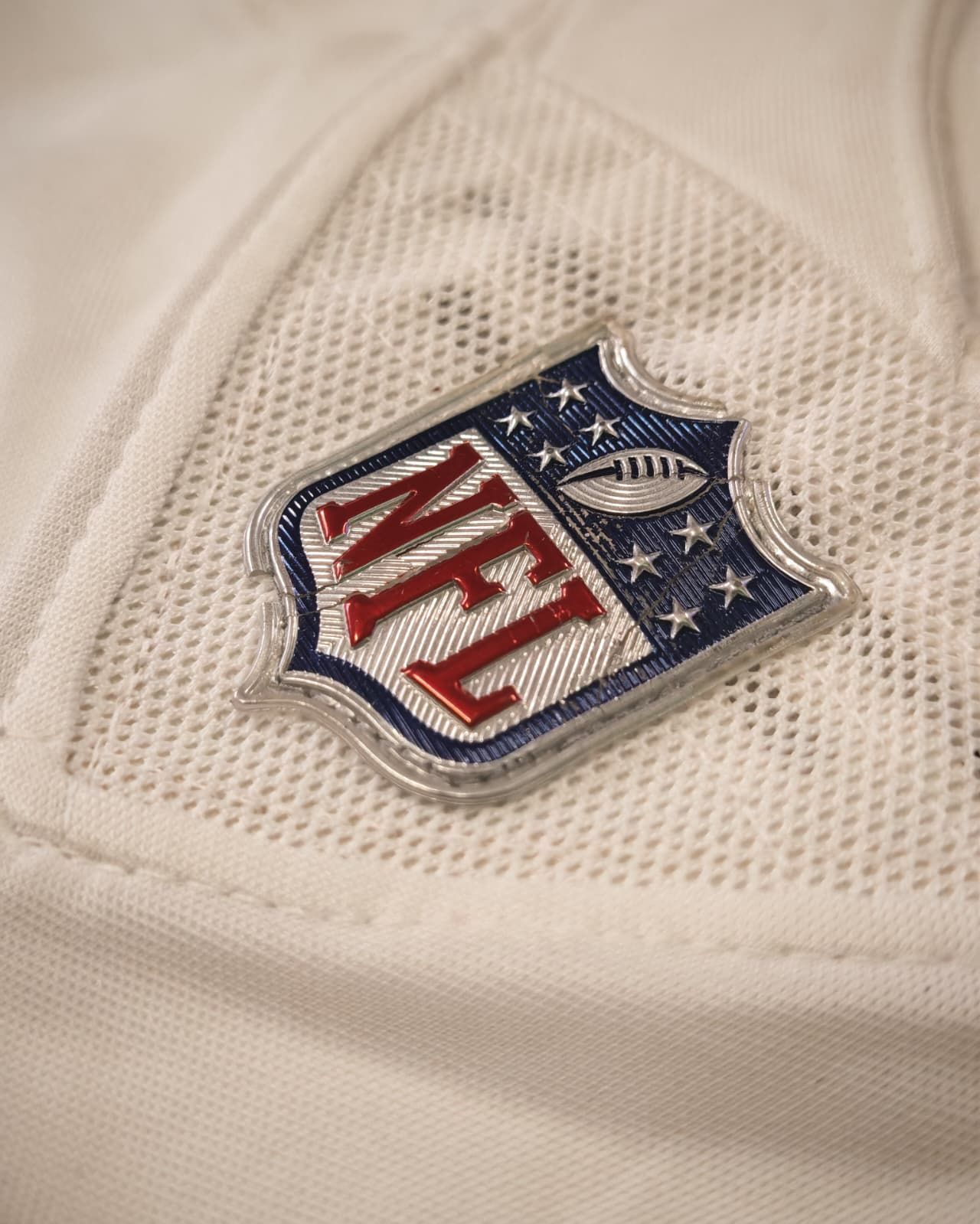 Primo piano di una maglia bianca della NFL con il logo a scudo rosso, bianco e blu della NFL.