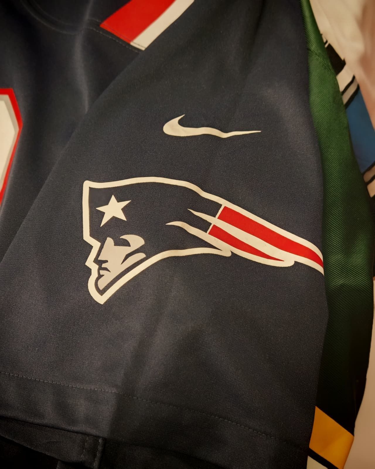 Maglia nera dei New England Patriots con logo Nike bianco e logo della squadra con strisce rosse.
