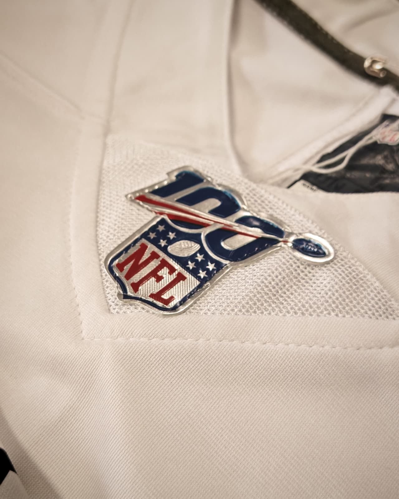 Primo piano di una maglia bianca della NFL con il logo dello scudo NFL cucito sul petto.