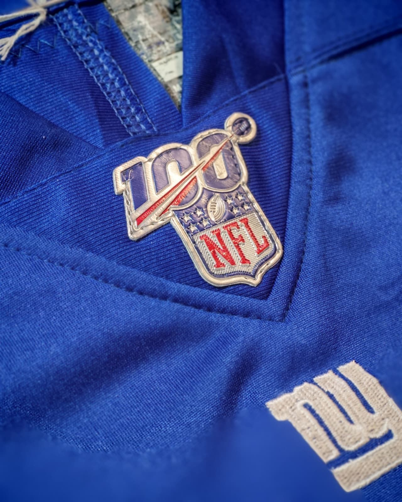 Primo piano di una maglia blu dei New York Giants con una patch per il centenario della NFL.