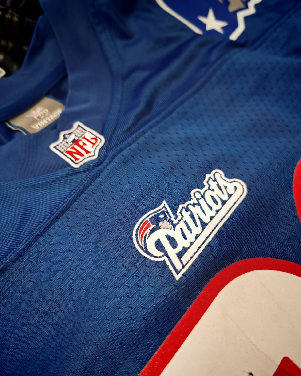 Maglia blu dei New England Patriots della NFL con dettagli rossi, bianchi e argento, vista ravvicinata.