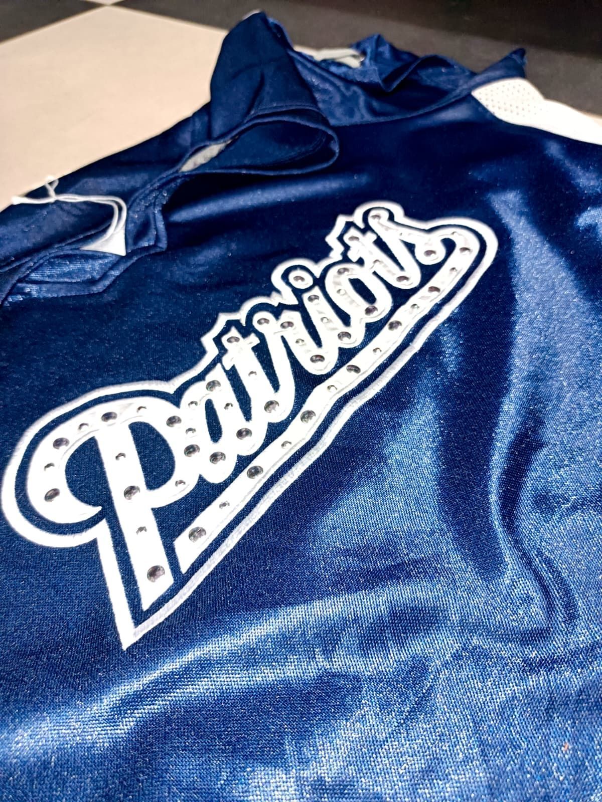 Felpa con cappuccio blu navy dei Patriots con grande logo bianco distesa su una superficie