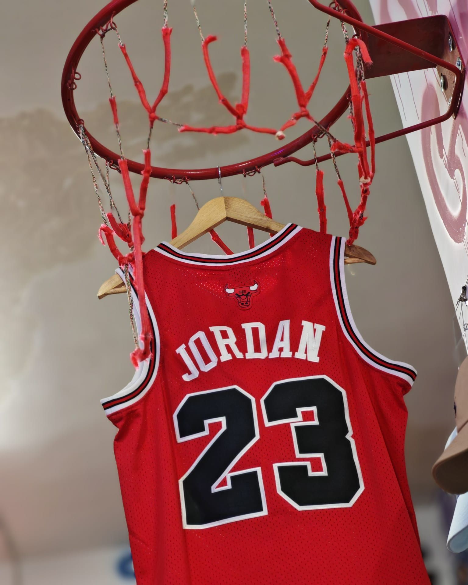 Maglia da basket rossa Jordan 23 appesa a un piccolo canestro con una rete rossa