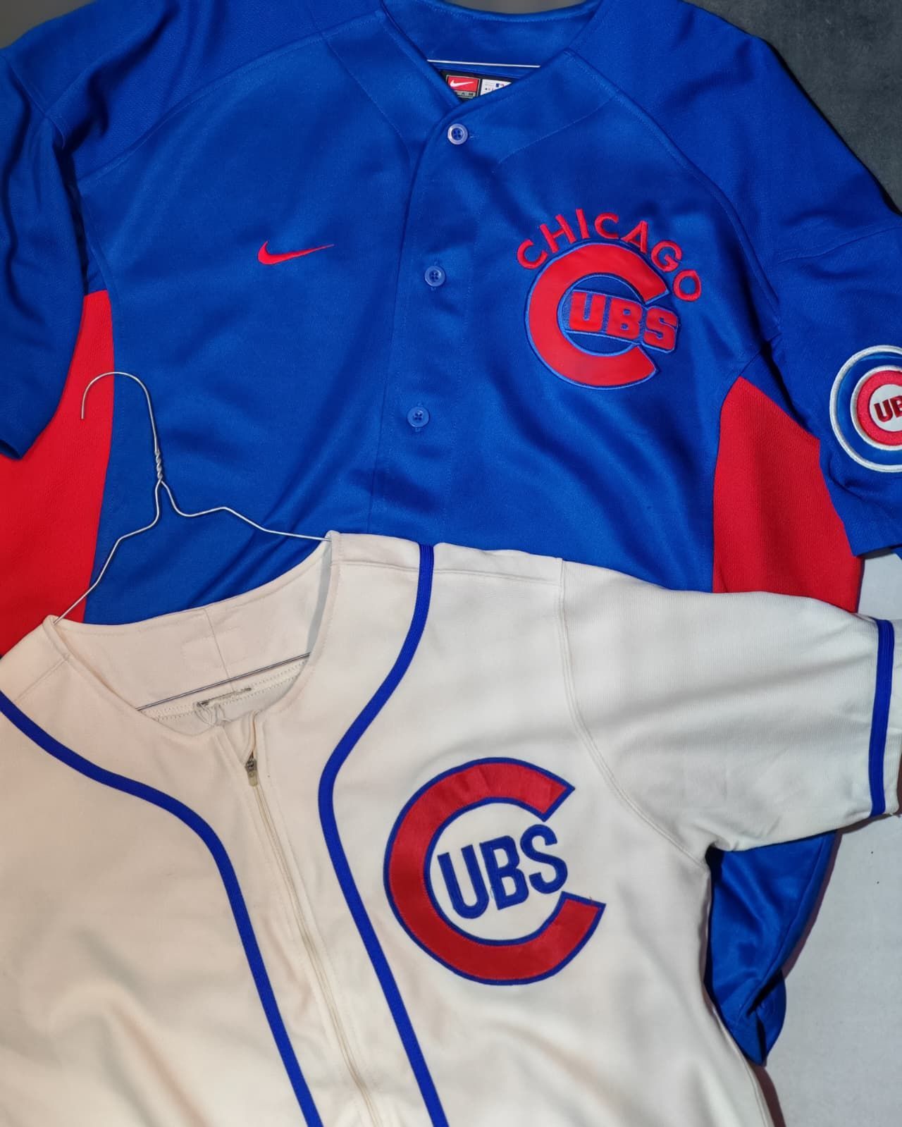 Due maglie da baseball dei Chicago Cubs, una blu reale e una bianca, disposte una accanto all'altra.