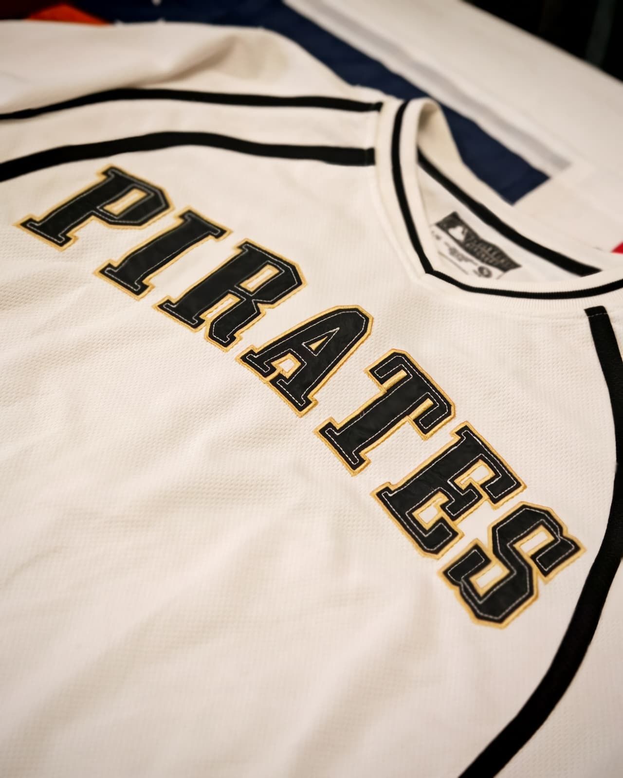 Maglia bianca dei Pittsburgh Pirates con scritte e strisce nere e oro.