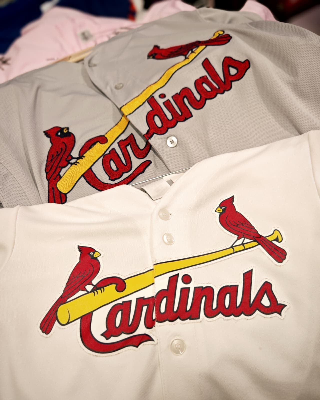 Maglie dei St. Louis Cardinals bianche e grigie con logo di un uccello rosso e la scritta Cardinals.