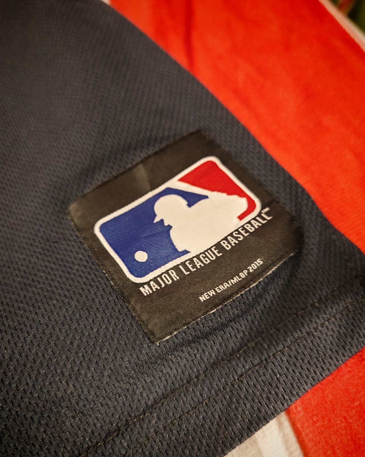 Primo piano di una patch con il logo della MLB su uno sfondo di tessuto nero testurizzato.