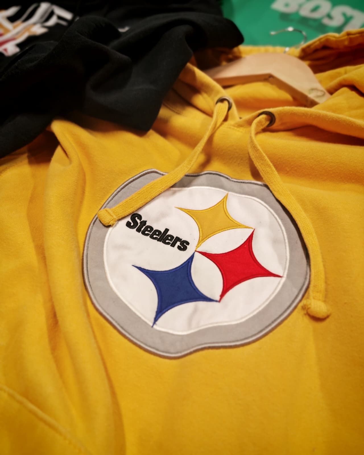 Felpa gialla con cappuccio e patch con il logo dei Pittsburgh Steelers sul petto, mostrata in primo piano.