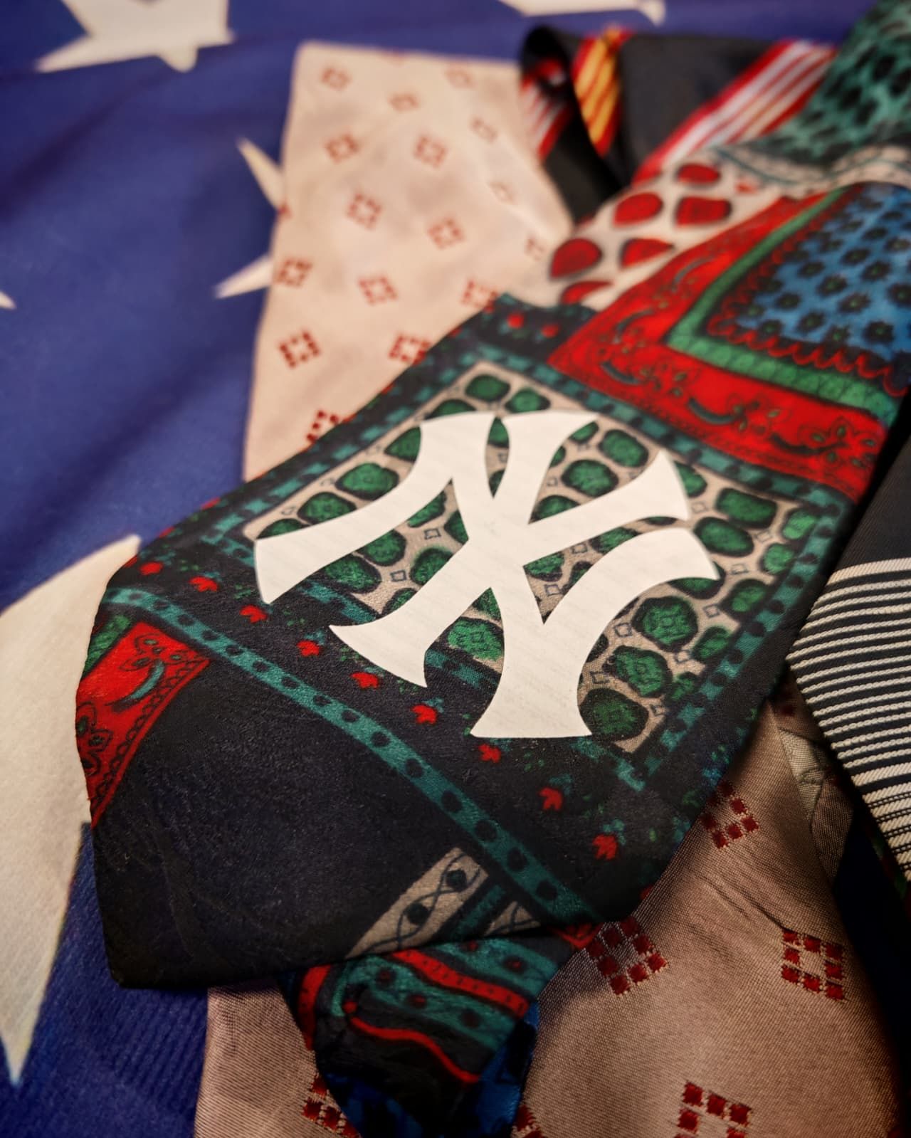 Cravatta fantasia con logo intrecciato bianco su tessuto rosso, verde e nero