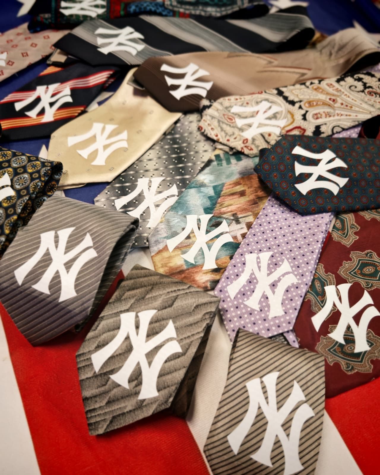 Cravatte assortite con i loghi dei New York Yankees, in vari colori e modelli, disposte su un tavolo.