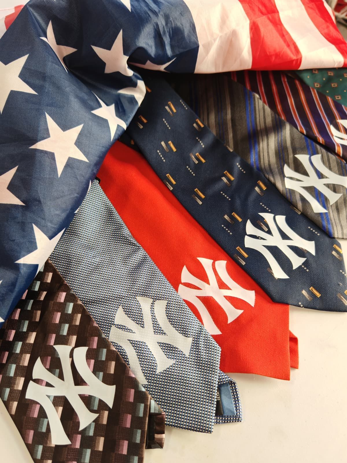 Cappellini impilati dei New York Yankees blu, rossi e grigi con loghi bianchi e motivo a bandiera americana.