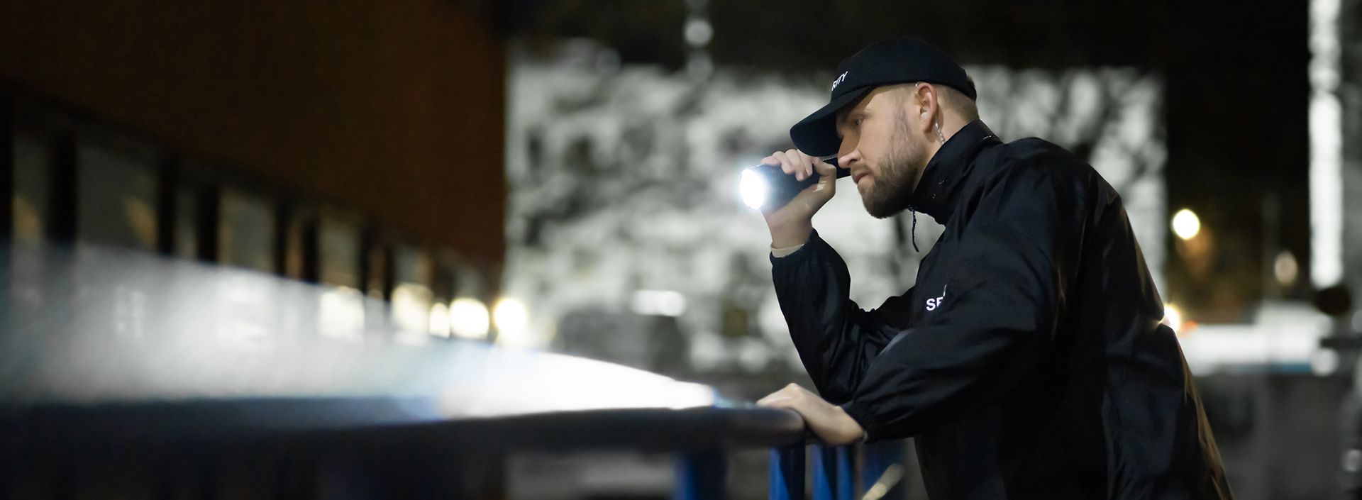 Security guard inspecting an area at night with a flashlight.