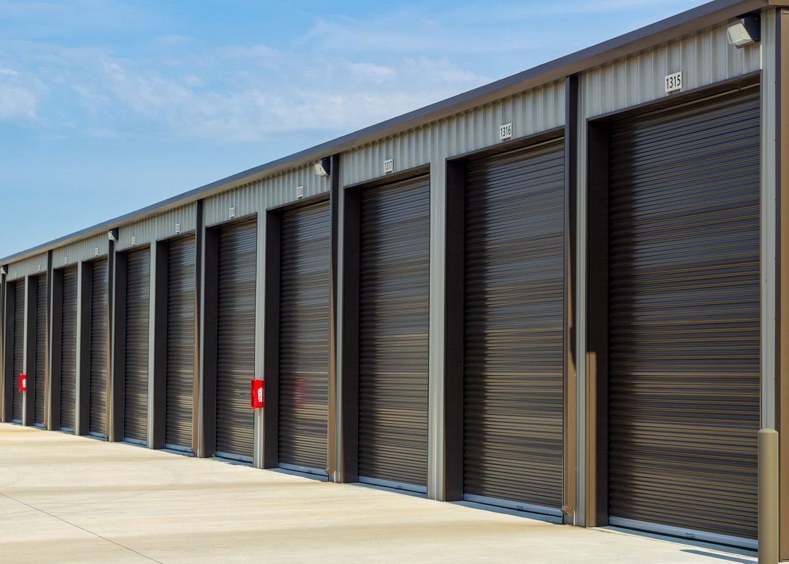 A row of storage units with roller doors on a sunny day.