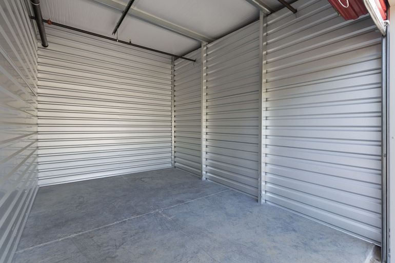 A white shipping container with orange shutters on the doors.