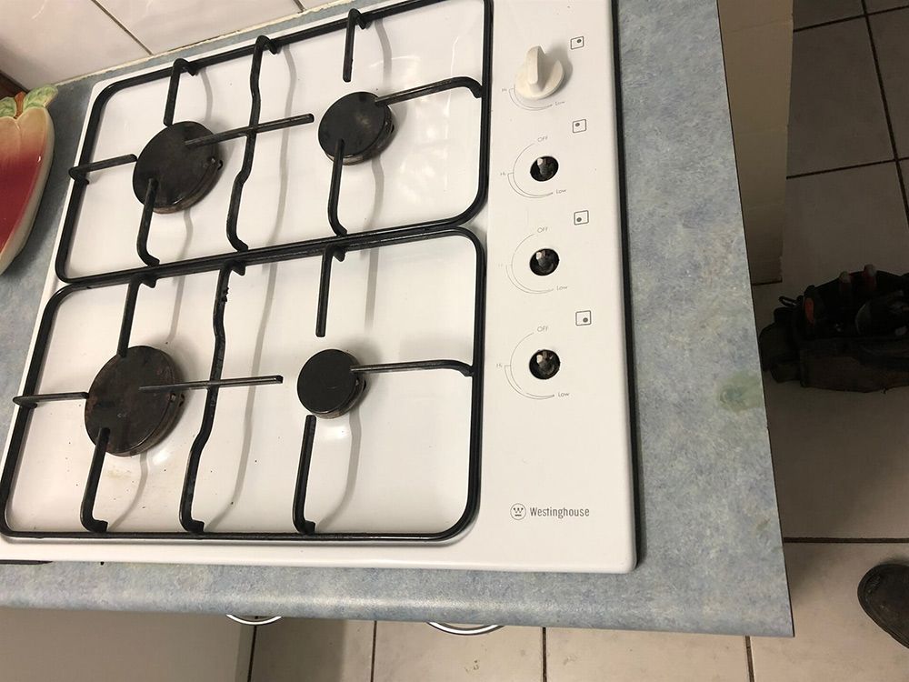 A White Gas Stove Is Sitting on Top of A Kitchen Counter — Plumbers & Gas Fitters in Coconut Grove, NT