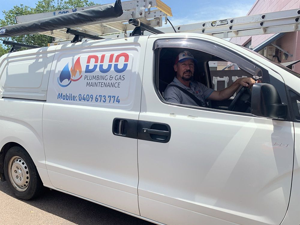 A Man is Sitting in the Driver 's Seat of a white van — Plumbers & Gas Fitters in Coconut Grove, NT