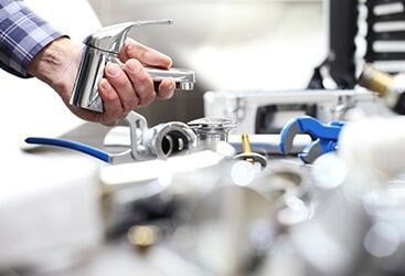 A Plumber is Fixing a Faucet in a Bathroom — Plumbers & Gas Fitters in Coconut Grove, NT