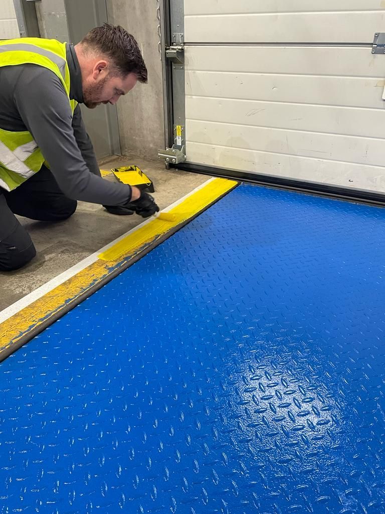 A man is kneeling down on a blue floor.