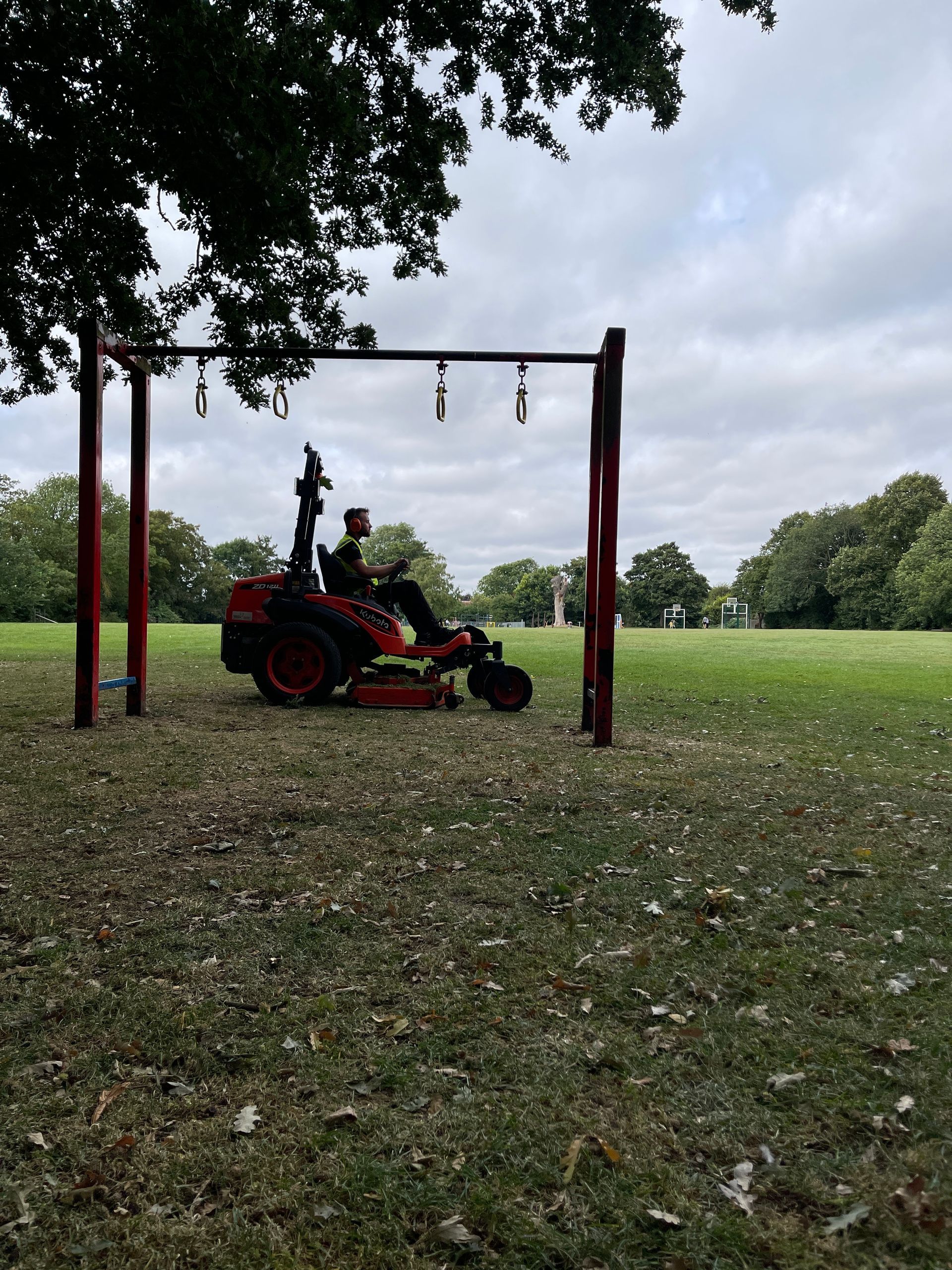 A man is riding a lawn mower in a park.