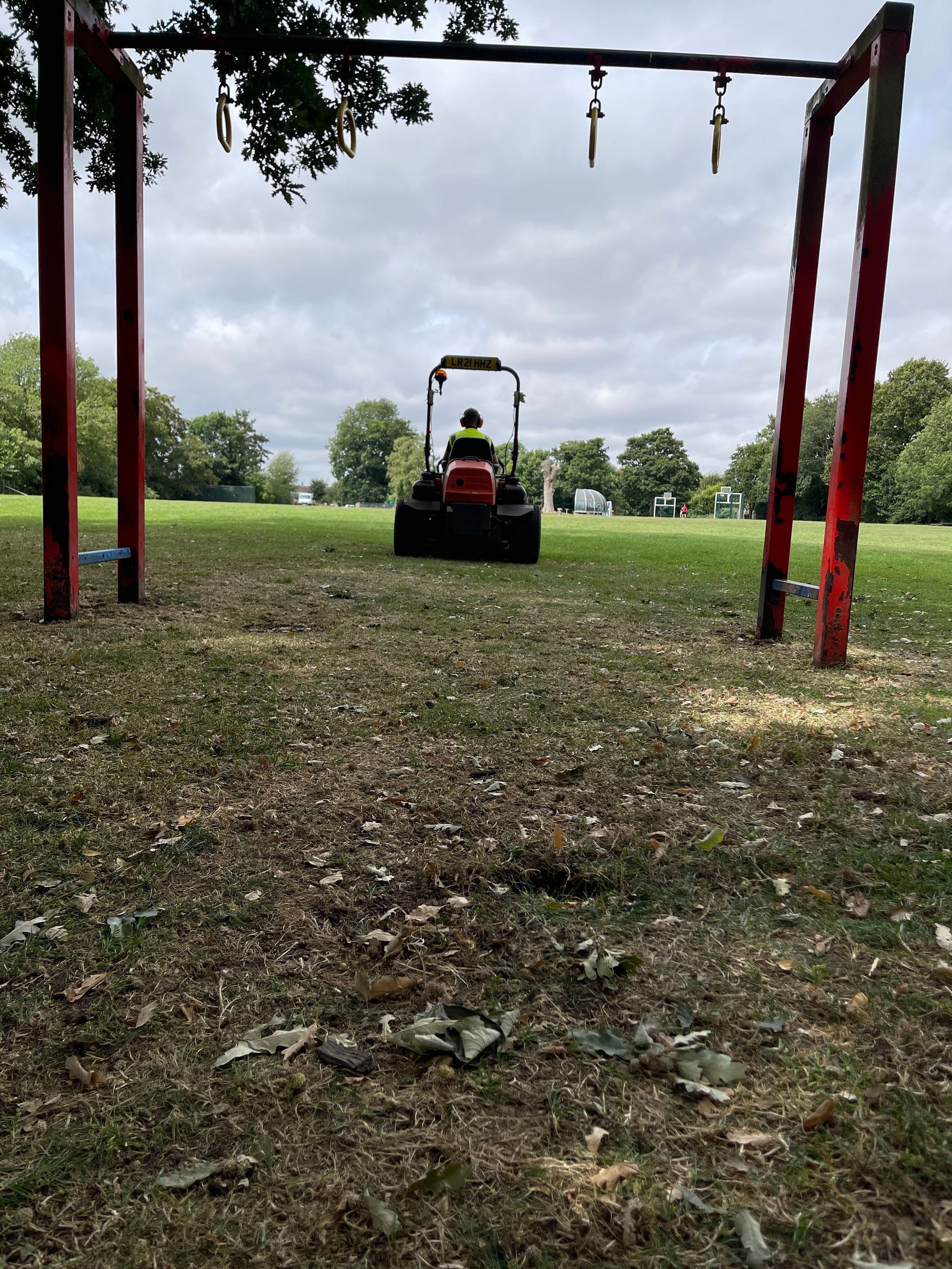 A person is riding a lawn mower in a park.