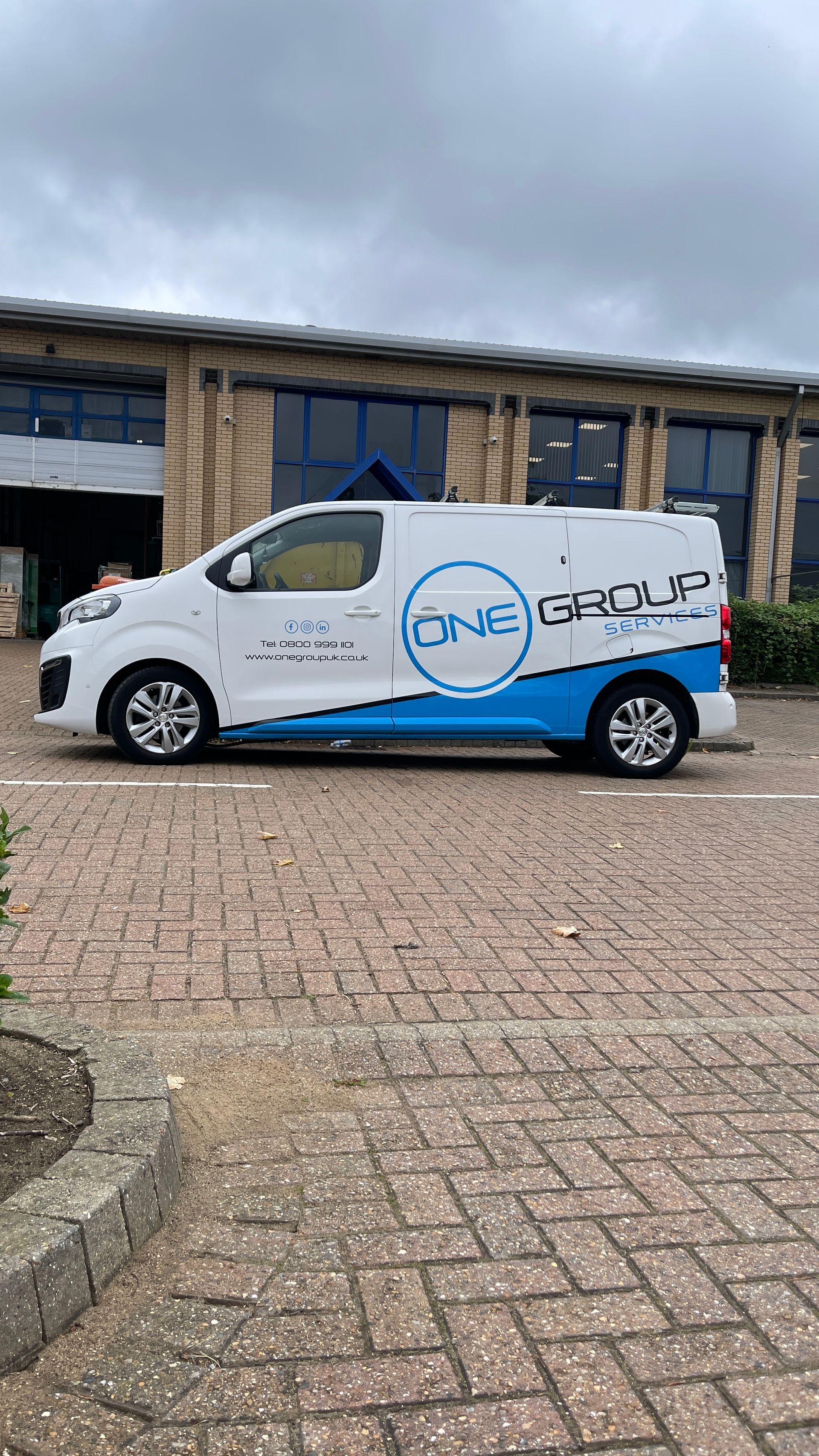 A white and blue van is parked in front of a building.