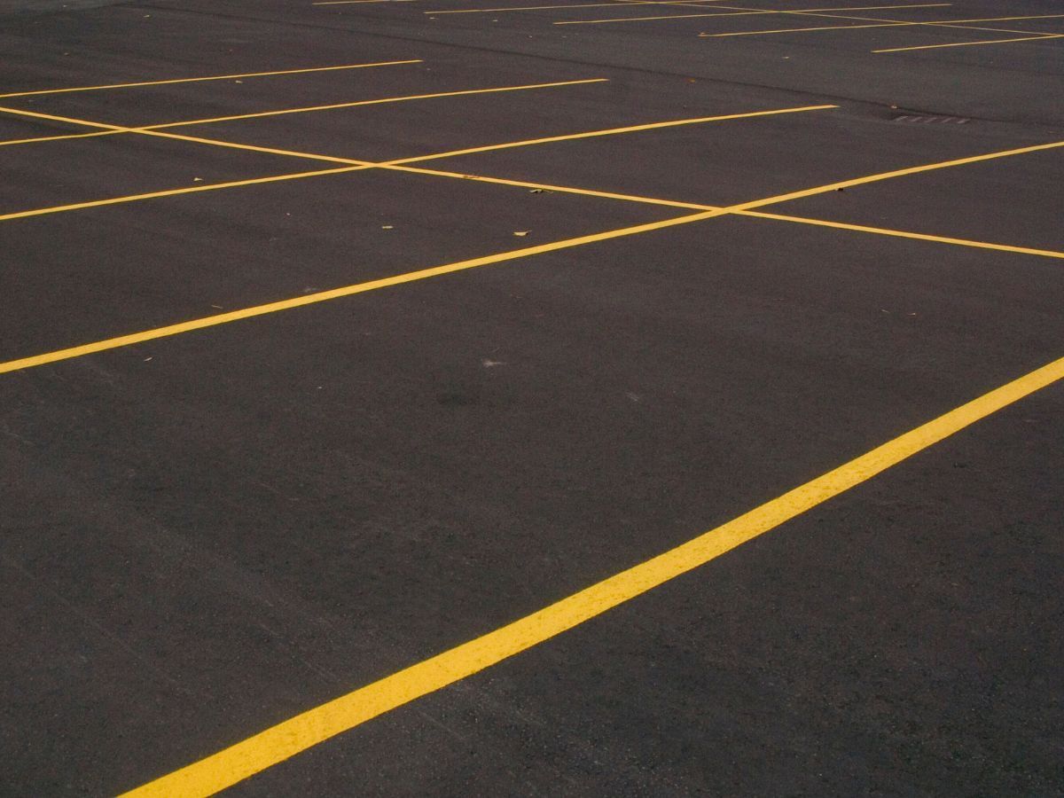 Empty dark asphalt parking lot with yellow painted parking lines