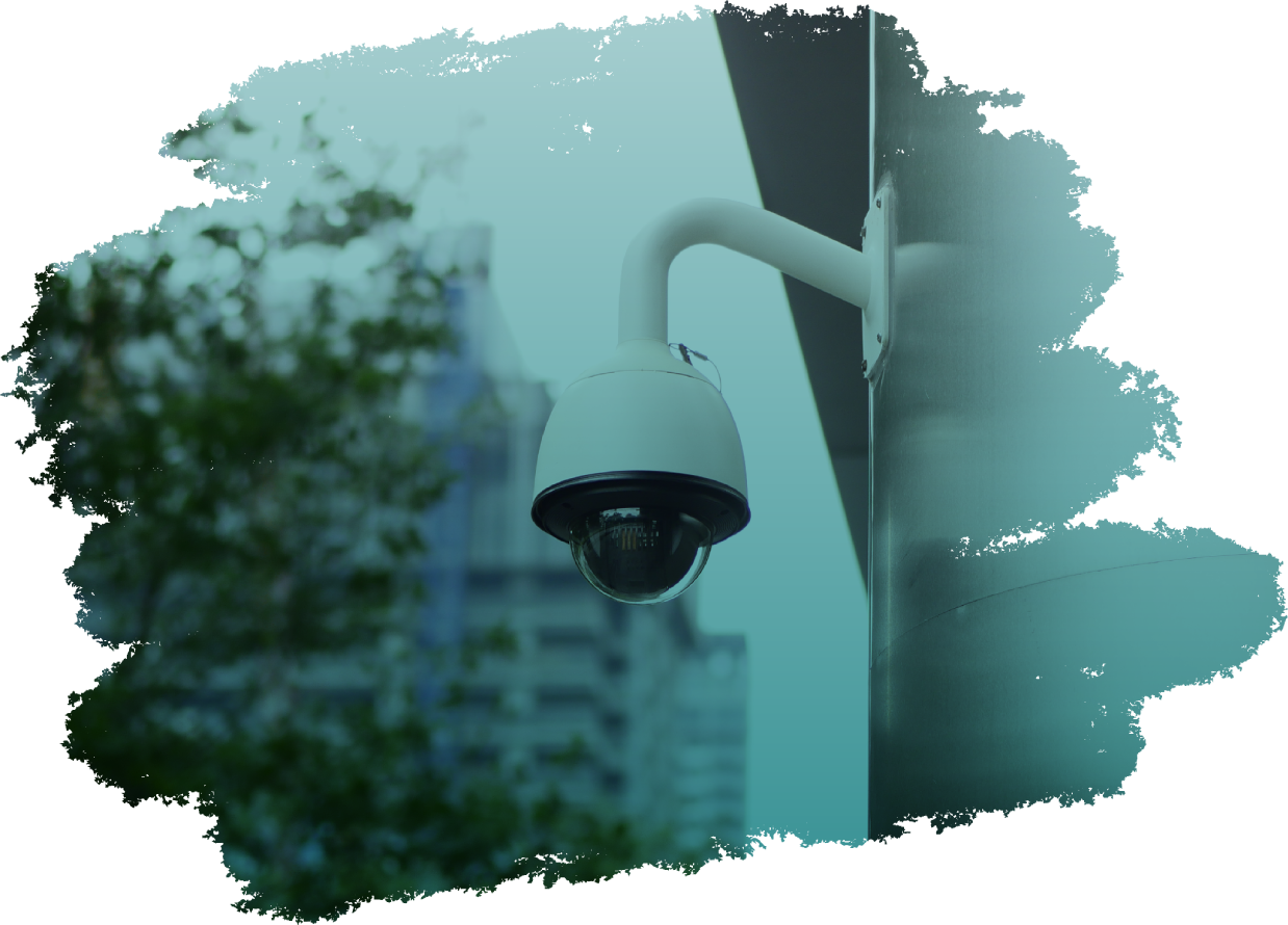 Uma câmera de segurança está pendurada em um poste em frente a um prédio.