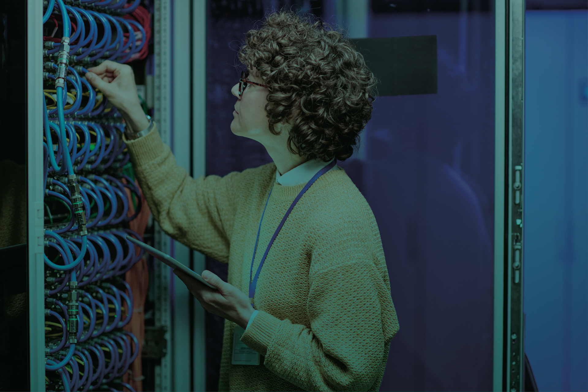 Uma mulher está trabalhando em um servidor em um data center enquanto segura um tablet.