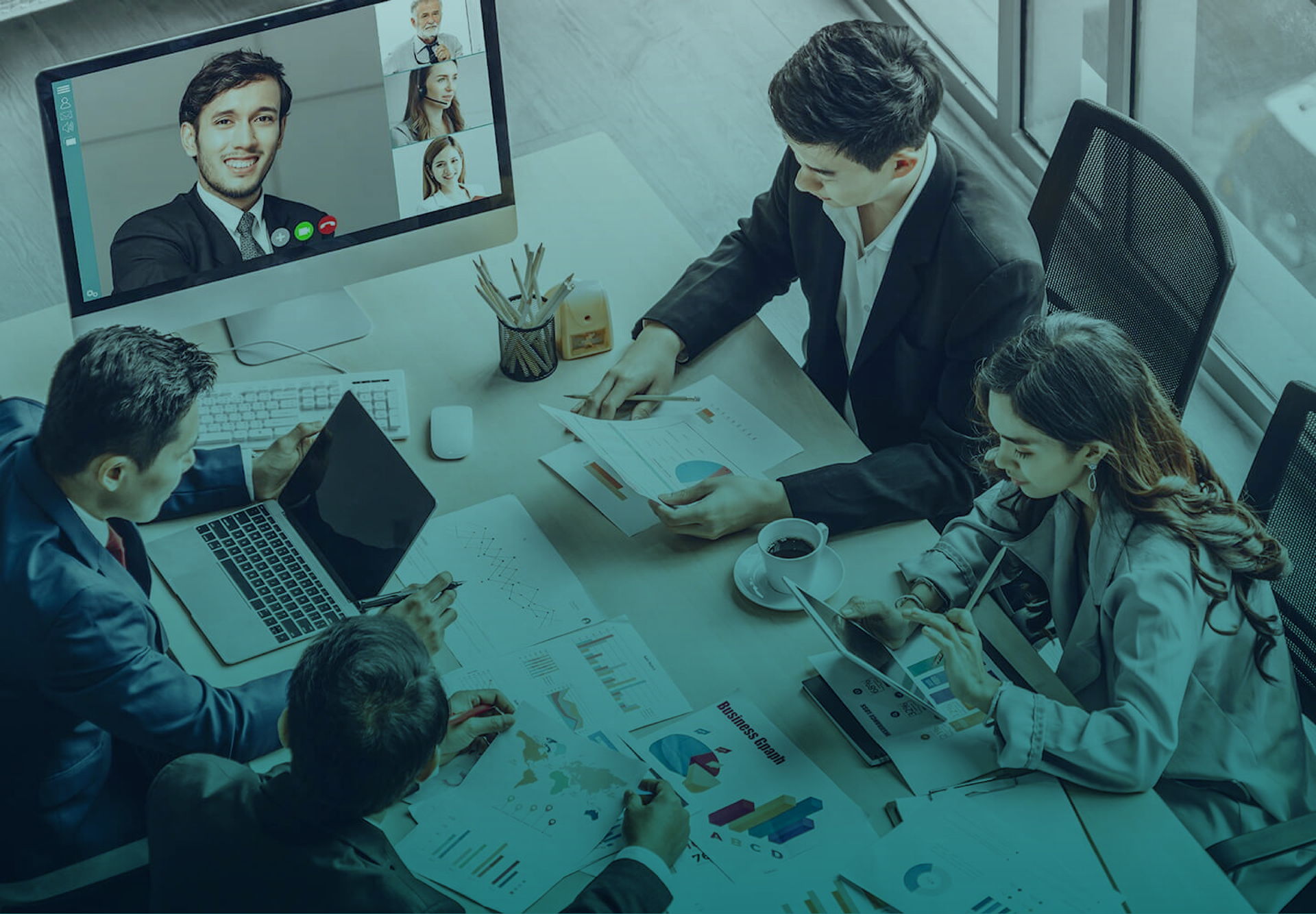 Um grupo de pessoas está sentado ao redor de uma mesa fazendo uma videoconferência.