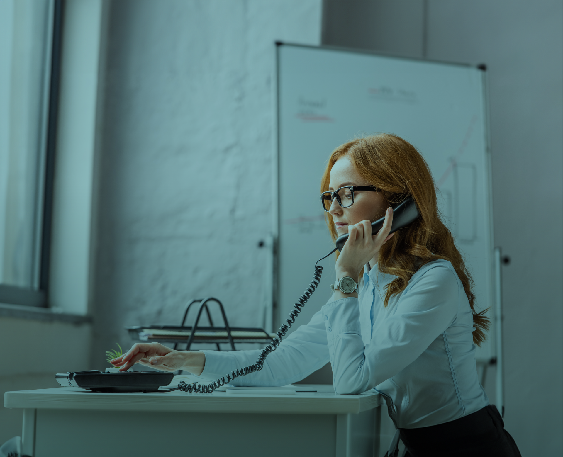Uma mulher está sentada em uma mesa falando ao telefone.