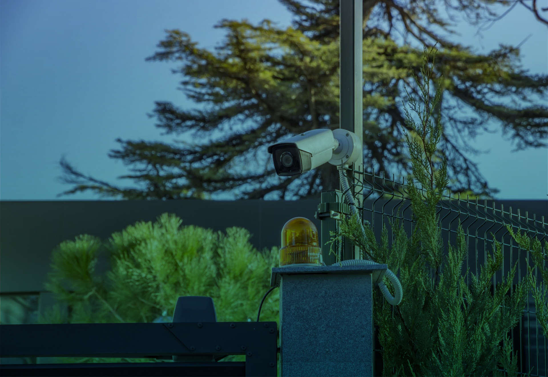 Uma câmera de segurança está montada em um poste em frente a uma cerca.