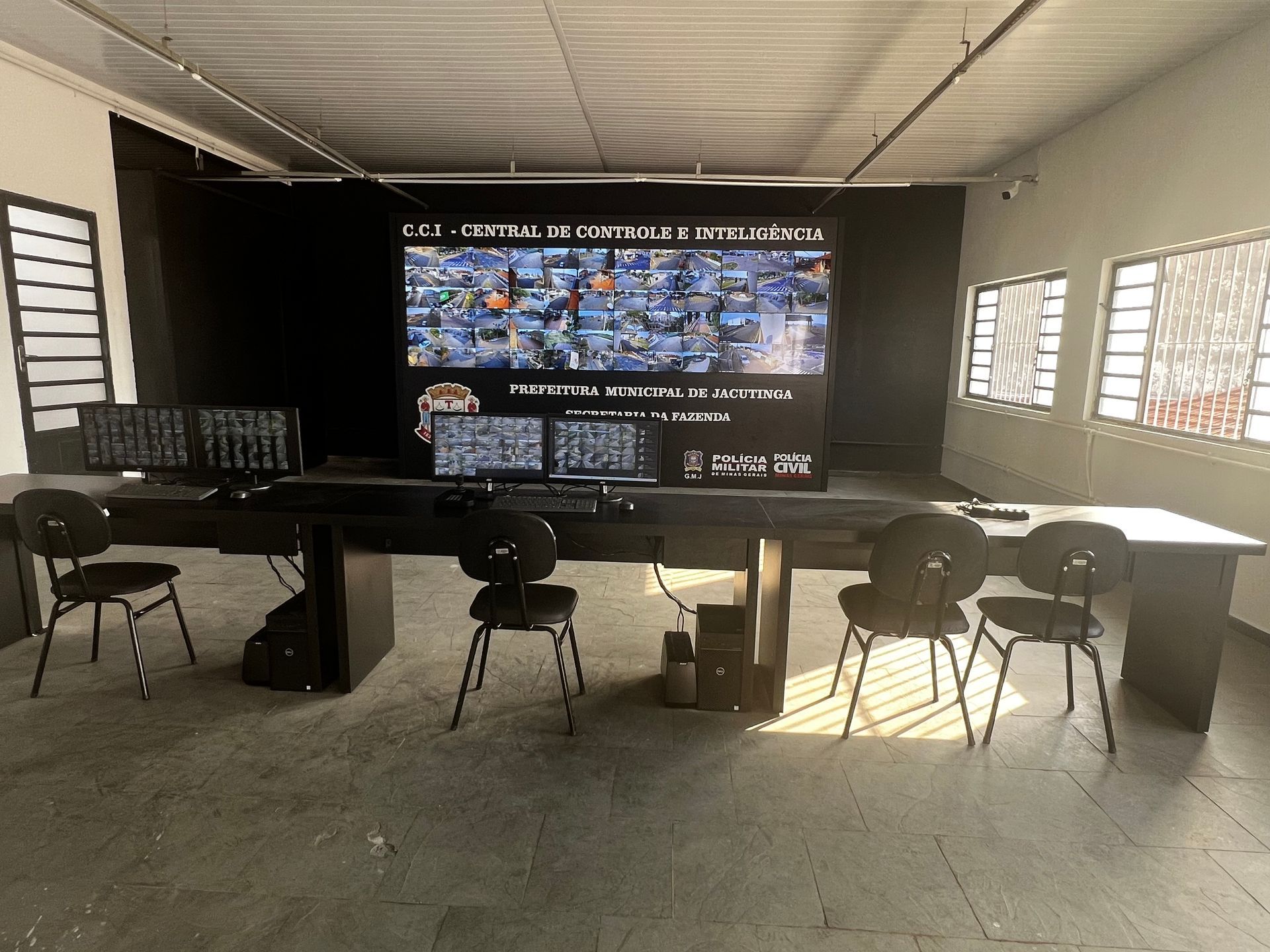 Uma sala com uma mesa e cadeiras e uma tela grande na parede.