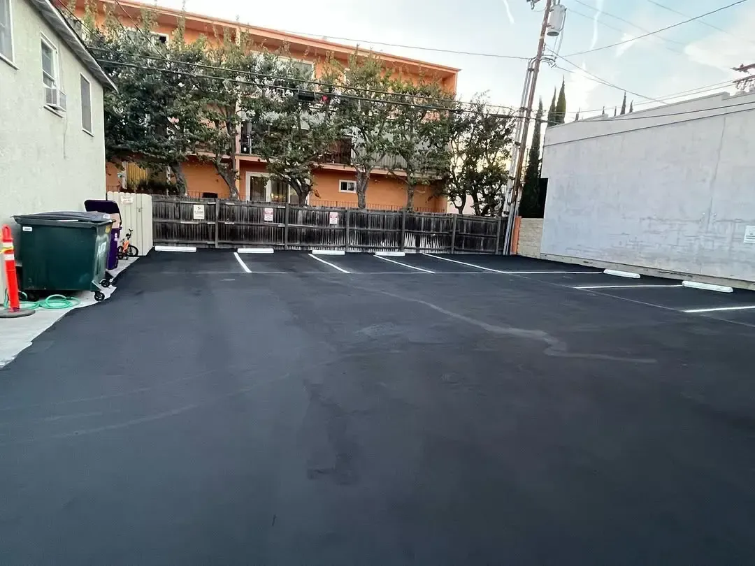A parking lot with a fence and a building in the background.