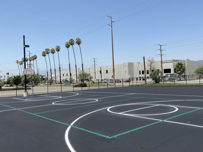 A basketball court with palm trees in the background