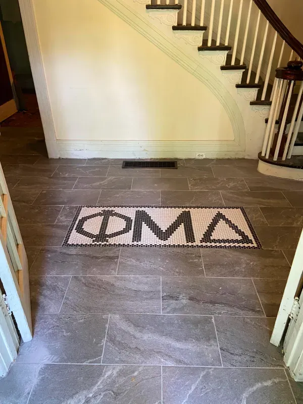A hallway with a staircase and a rug on the floor.
