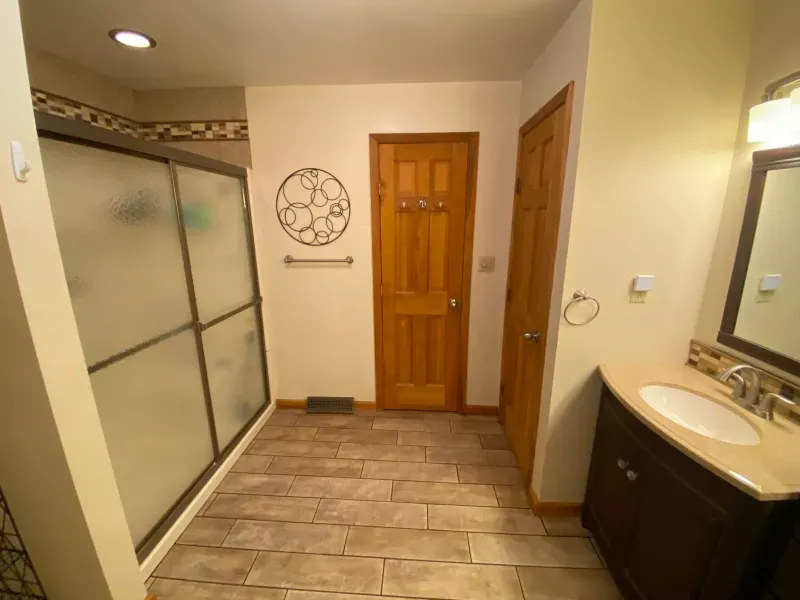 A bathroom with a sliding glass shower door and a sink.