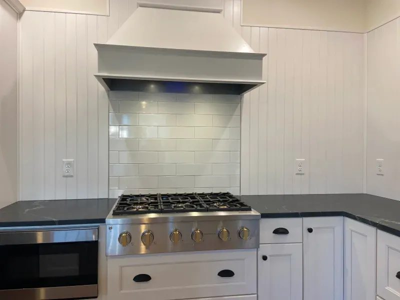 A kitchen with white cabinets and a stove top oven