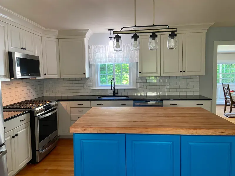 A kitchen with blue cabinets and a wooden counter top.
