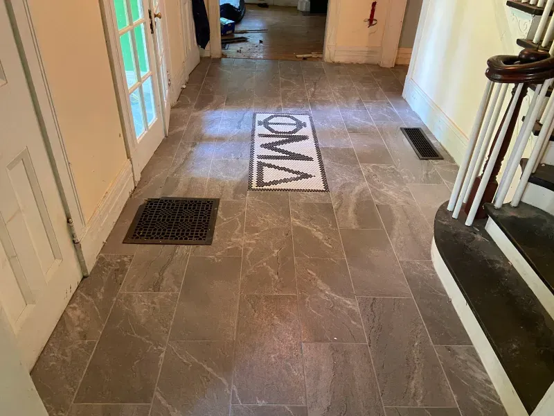 A hallway with a rug on the floor that says oma