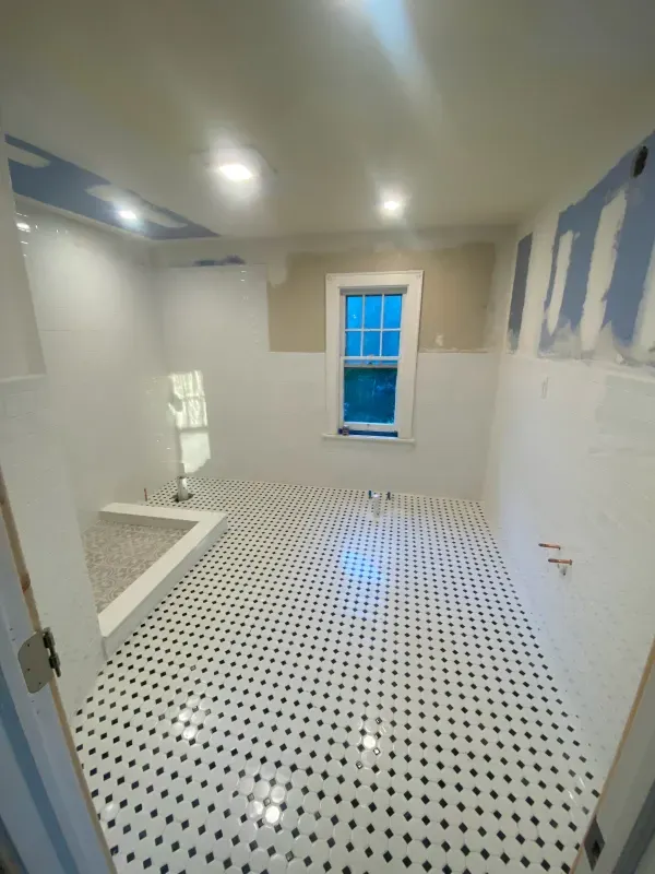 A bathroom with white tile floors and a window.