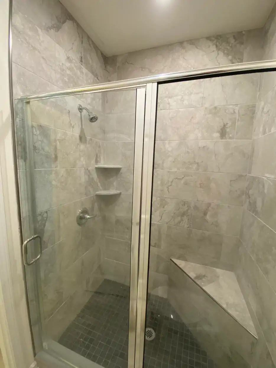 A bathroom with a walk in shower with a glass door.